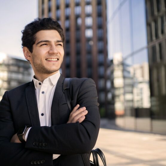 A businessman goes to work in the office in a business suit, smiles and thinks about the project.