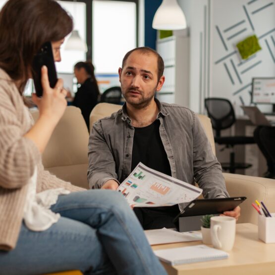 Employee taking at smartphone with business partner