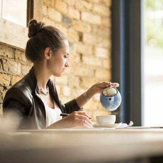 Young businesswoman pouring tea in cafe
